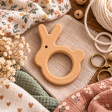 Création DIY en cours avec anneau de dentition lapin en bois naturel, tissus fleuris, cordon macramé et accessoires de couture.