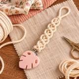 Attache-tétine DIY en macramé avec pince en silicone rose, corde écrue et matériel de couture sur tissu naturel
