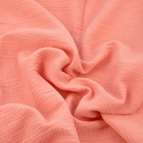 Gros plan sur la texture froissée d'une double gaze de coton corail