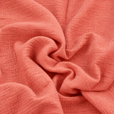 Gros plan sur la texture froissée d'une double gaze de coton corail