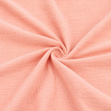 Double gaze de coton saumon présentée en gros plan pour révéler sa texture douce et froissée